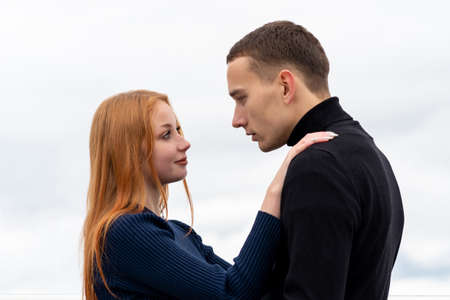 young couple man and woman stands hugging on the background of a cloudy skyの写真素材