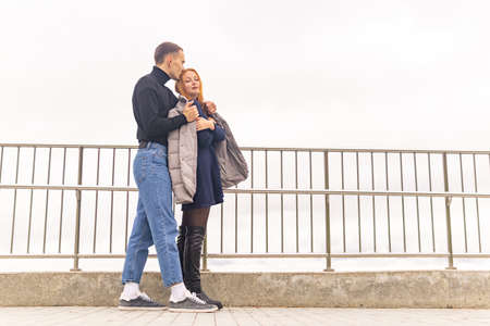 couple in love, the guy puts his jacket on the girl's shoulders in cold weatherの写真素材