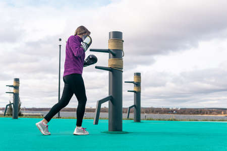 young woman practicing martial arts alone on the sports ground with traditional dummies outdoorsの写真素材