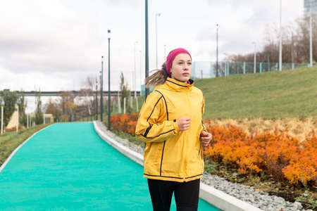 young woman jogging on all-weather running track in an urban environmentの写真素材