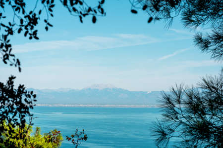sea bay with a distant mountainous coast, a view from the mountain through tropical vegetation on the coast of Antalyaの写真素材