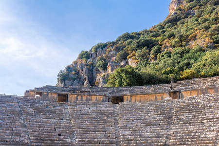 sunlit ruins of antique amphitheater against the backdrop of the famous rocky necropolis in Myra...