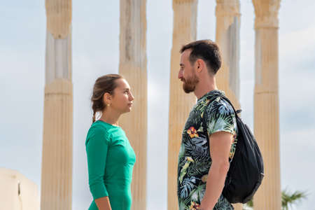 couple of tourists man and woman look at each other against the background of ancient columns