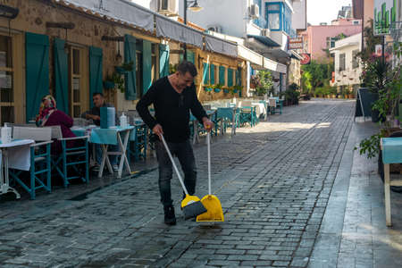 Antalya, Turkey - November 15, 2021: owner of a street restaurant is sweeping next to his...