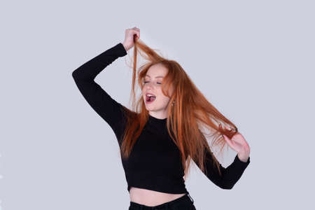 young woman with tousled hair stretches on a light background