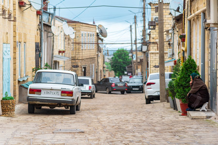 Derbent, Russia - May 09, 2022: old woman sits thoughtfully on the street in the historical quarter of Derbent, Dagestanのeditorial素材