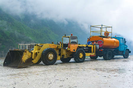 heavy road equipment for landslide raking stands by the roadside in a mountainous area during stormy weatherの写真素材