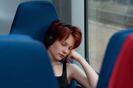 young woman dosed off sitting in a chair in a suburban train carの写真素材