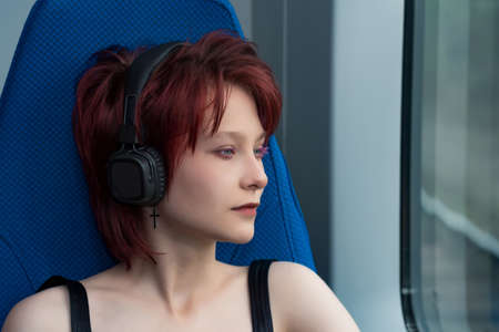 young woman listening to music with headphones while riding on a high-speed trainの写真素材