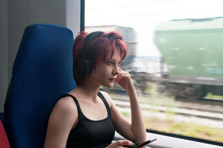 young woman listening to music while riding in a suburban train carの写真素材