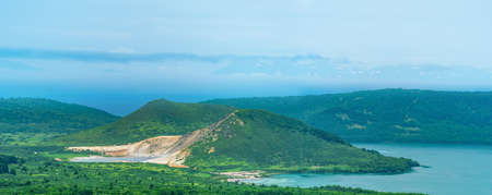 landscape of Kunashir Island, lakes and lava domes in the center of Golovnin volcano caldera; the island of Hokkaido is visible in the distance in the seaの写真素材