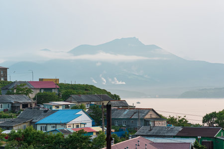 landscape of the town of Yuzhno-Kurilsk on the island of Kunashir with a view of the sea bay and the Mendeleev volcano in the distanceの写真素材