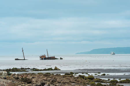 seascape with a shipwreck in the foreground and a small fishing vessel at sea in the backgroundの写真素材
