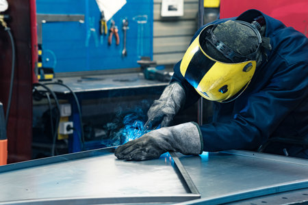 welder at work, welding metal parts in workshop