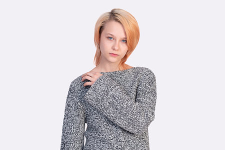 girl teenager in a sweater looks into the frame isolated on a white backgroundの写真素材
