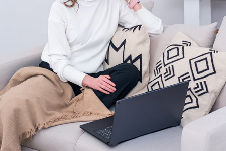 woman sitting on sofa indoor working with laptopの写真素材