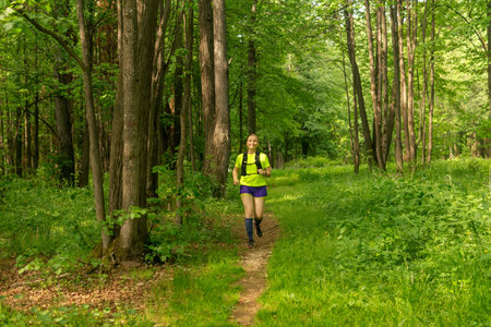 young woman jogging on a path in a natural forest parkの写真素材