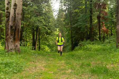 young woman jogging on a trail in a natural forest parkの写真素材