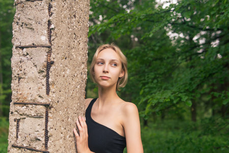 young woman posing next to the only concrete pillar among the natural landscape