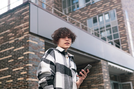 young man with a phone on the background of city buildings