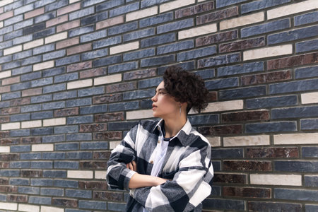 young man posing against a brick wall