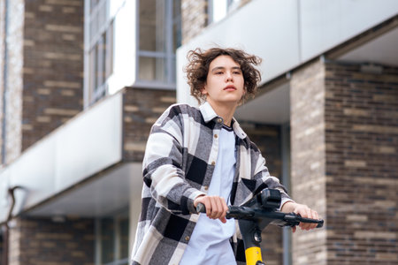 young man on an electric scooter rides down the streetの写真素材