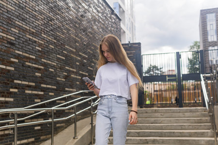 young woman with a phone on the background of city buildingsの写真素材