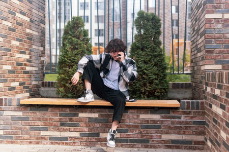 young man talking on the phone while sitting on a bench in the cityの写真素材