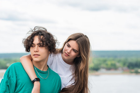 couple of young people hugging against a blurred river landscapeの写真素材