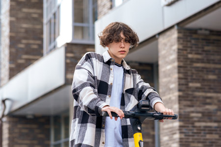 young man on an electric scooter rides down the streetの写真素材