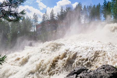 turbulent stream during an idle discharge of water against the background of a building of a small hydroelectric power stationの写真素材