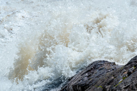 muddy turbulent stream under a rock during high waterの写真素材