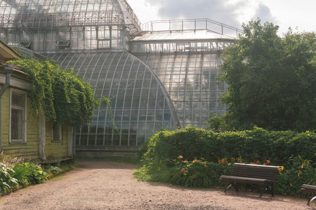 corner of an old botanical garden with a huge vintage greenhouse in the backgroundの写真素材