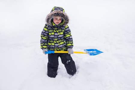 little boy playing in the snow in winterの写真素材
