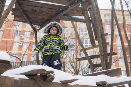 little boy playing in a tree house built by children in snowy winterの写真素材