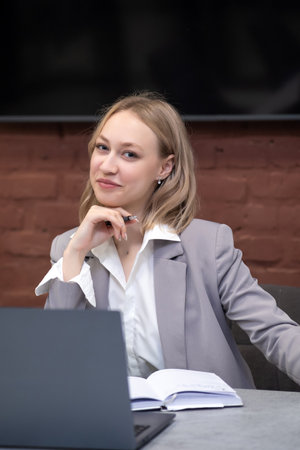 Portrait of a young businesswoman sitting at a table with a laptopの写真素材