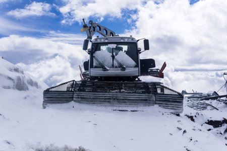 Snowcat in the snow in the highlands against the background of a blue sky with white clouds.の写真素材