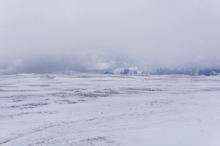landscape of glacial highland plateau, view from the surface of the glacier, mountains in the clouds are visible in the distanceの写真素材