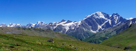 panoramic mountain landscape with green highland valley, observatory in the distance and mountain peaks in the backgroundの写真素材