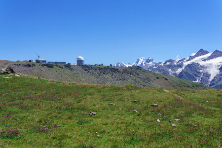 mountain landscape with alpine meadow, observatory in the distance and mountain peaks in the backgroundの写真素材