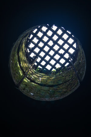 view from the dungeon upwards through a hatch covered with a grateの写真素材