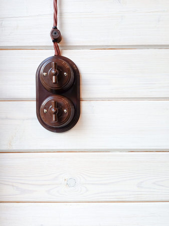 Vintage electric light switch hanging on a white wooden wall with copy space