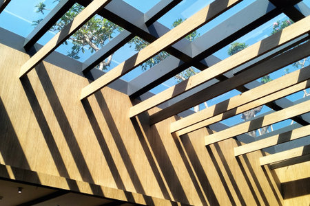 Wooden ceiling in a modern building with blue sky and trees.