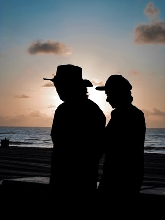 Silhouette of two men at sunset on the beach in summerの写真素材