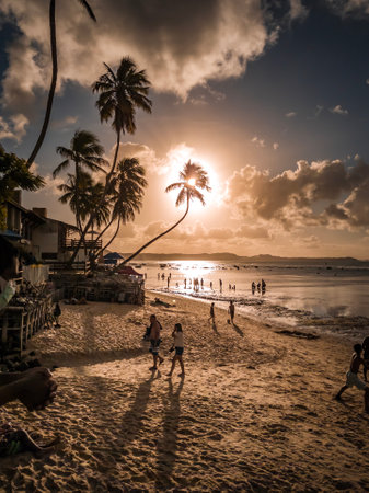 Tropical beach at sunset with silhouettes of people and palm treesの写真素材