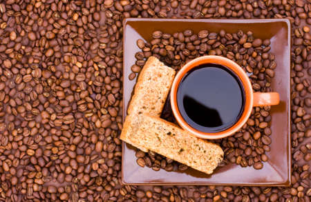Cup of black coffee with beans and rusks viewed from the topの写真素材