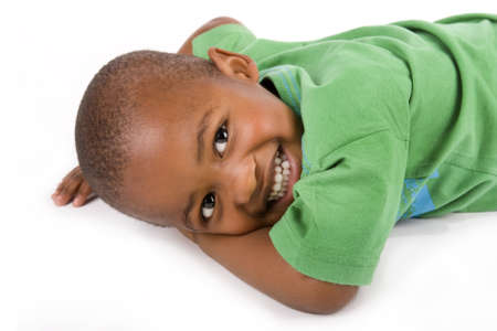 Adorable 3 year old black or African American boy with a smile laying on the floor looking at youの写真素材
