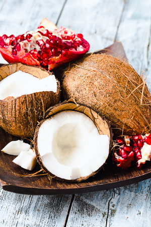 Fresh coconut and red garnet in a wooden bowl,blue background, tropical fruit,selective focusの写真素材