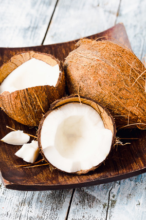 Fresh coconuts in the shell in a wooden bowl on a blue background, tropical fruit, selective focusの写真素材