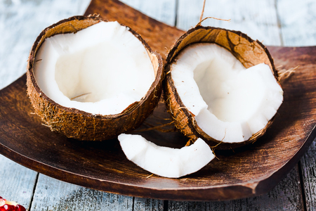 Fresh coconuts in the shell in a wooden bowl on a blue background, tropical fruitの写真素材